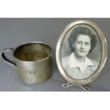 A sterling silver photograph frame, oval with easel and a small sterling silver mug initialled F.W.W