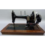 An early 20th century Naomann hand sewing machine black japanned with gilt decoration, the base