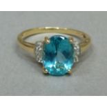 A blue topaz and diamond three stone ring in 14ct gold, claw set to the centre with an oval facetted