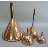 A large copper hops funnel, 30.5cm together with three smaller funnels, two with strainers