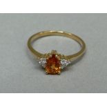 A citrine and cubic zirconia ring in 9ct gold claw set to the centre with a pear shaped citrine