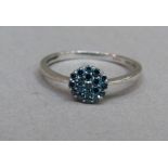 An iradiated blue diamond cluster ring in 9ct white gold, the brilliant cut stones claw set within a