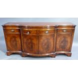 A reproduction mahogany sideboard in George III style with cross grained border above a bowed centre