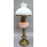 A Victorian brass oil lamp having a pink glass reservoir moulded with plant forms, the reeded column