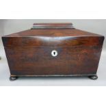 A Regency rosewood tea caddy of sarcophagus shape with draft turned side handles, the interior