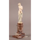 A 19TH CENTURY CARVED IVORY FIGURE OF A SEMI-DRAPED NUDE FEMALE, standing, on a circular base and