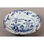 AN 18TH CENTURY DUTCH TIN GLAZED CIRCULAR DISH painted in underglaze blue with flowers and fence
