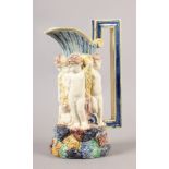 A VICTORIAN MAJOLICA JUG, modelled as a ring of cherubs standing upon a rocky base, reeded neck