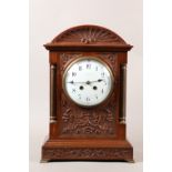 AN EDWARD VII MAHOGANY CASED MANTEL CLOCK, the arched top shell carved above a flared cornice, the