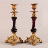 A PAIR OF 19TH CENTURY RUBY GLASS AND ORMOLU CANDLESTICKS with foliate cast nozzles and scroll