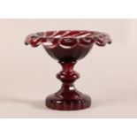 A RUBY CASED CUT GLASS TAZZA of everted shallow urnular form, the rim spiral and oval cut, knopped