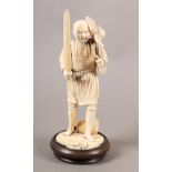 A JAPANESE IVORY OKIMONO, carved as a fisherman standing holding a spear, a cormorant on his
