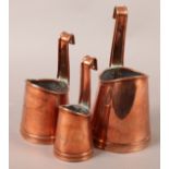 AN EARLY 20TH CENTURY SET OF THREE COPPER LADLES of graduated size, tapered, with strapwork