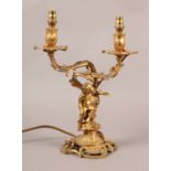 A GILT METAL TWIN LIGHT TABLE LAMP, early 20th century, of rococo style mounted with cherub, 32cm to