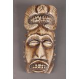 A BONE MASK OF ANTHROMORPHIC FORM with 'curled horn' headdress, the face with bulging oval eyes