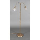 A BRASS PEDESTAL STANDARD LAMP with pair of articulated arms with ribbed frilled glass shades,