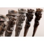 A SET OF FIVE BRONZE CANDLESTICKS each depicting a Jewish speculator with happy face, the figures