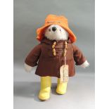 A modern Paddington bear with orange felt hat, brown felt jacket and yellow wellingtons