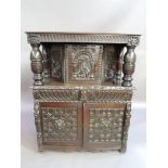An oak court cupboard the fluted frieze with lion mask to each side above a pair of massive turned