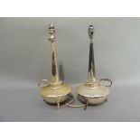 A pair of silver plated lamps with tapered columns and circular reservoirs with loop handle and