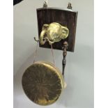 A dinner gong, the oak back plate set with brass elephant head, the gong supported on the trunk,