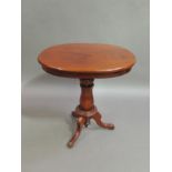 An oval topped tripod table, the figured top above a shallow frieze on a chamfered baluster column