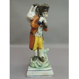 An 18th century Yorkshire pottery figure of a shepherd with sheep over his shoulder, standing before