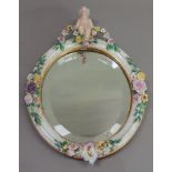 A Continental porcelain floral encrusted oval mirror, the bevel plate within a frame set to the