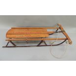 A Lightening Glider sledge, the oak frame with metal runners, steering section to front, 98cm long