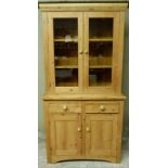 A reproduction pine bookcase cupboard the top enclosed by a pair of glazed doors, the projecting