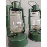 A pair of green painted Gael Brooder tilley style lamps, 52cm high