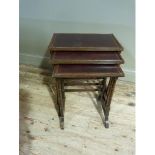 A nest of three mahogany occasional tables having leather incised surfaces and on slender ring