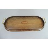 A two handled oak tray of oval ended rectangular form, the centre inlaid with a shaded shell paterae