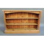 A reproduction pine open bookcase the rectangular top above an arched frieze, the sides fluted and