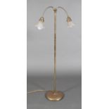 A brass pedestal standard lamp with pair of articulated arms with ribbed frilled glass shades,
