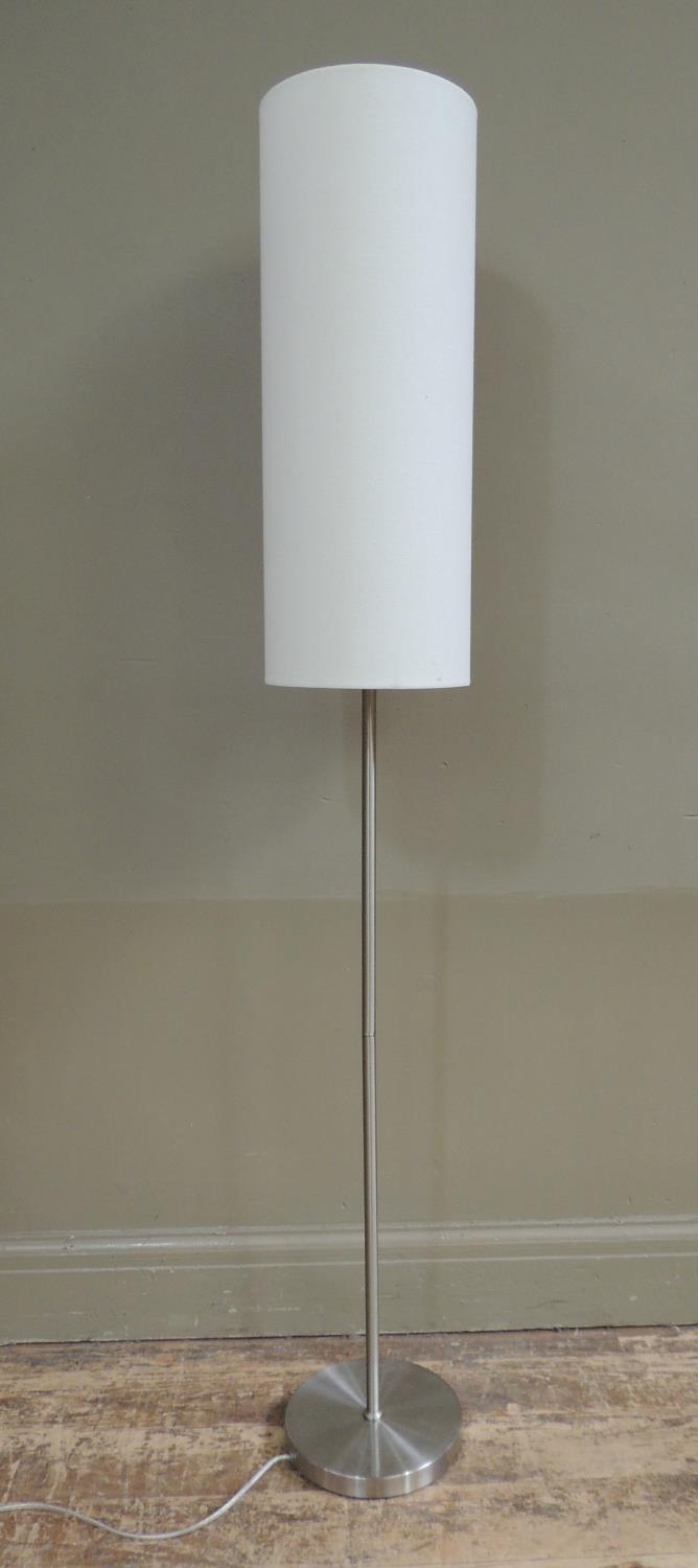 A brushed steel standard lamp with tall cylindrical white shade, 150cm high