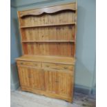 A reproduction pine dresser, the boarded and shelved back above a projecting front fitted with