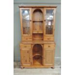 A reproduction pine dresser, the top with pair of glazed cupboards flanking an arched shelved