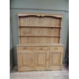 A pine dresser with boarded and shelved back, projecting base fitted with three short drawers