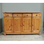 A reproduction pine dresser base, fitted with four short drawers and four panelled cupboards,