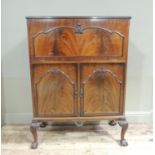 A 1930s mahogany drinks cabinet, the hinged top revealing mirrored interior with provision for