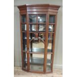 A mahogany display cabinet with flared cornice, shallow frieze, enclosed by a single arched glazed