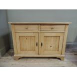A pine sideboard the rectangular top above two short drawers and pair of panelled cupboard doors,