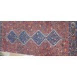 A late 19th/early 20th century carpet having a mid red ground, four blue and ivory bordered