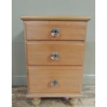 A pine chest of drawers the top with applied ovolo edge above three graduated drawers, turned wooden