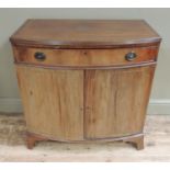 A mahogany bow front cabinet having a single drawer above a two door cupboard on splayed bracket
