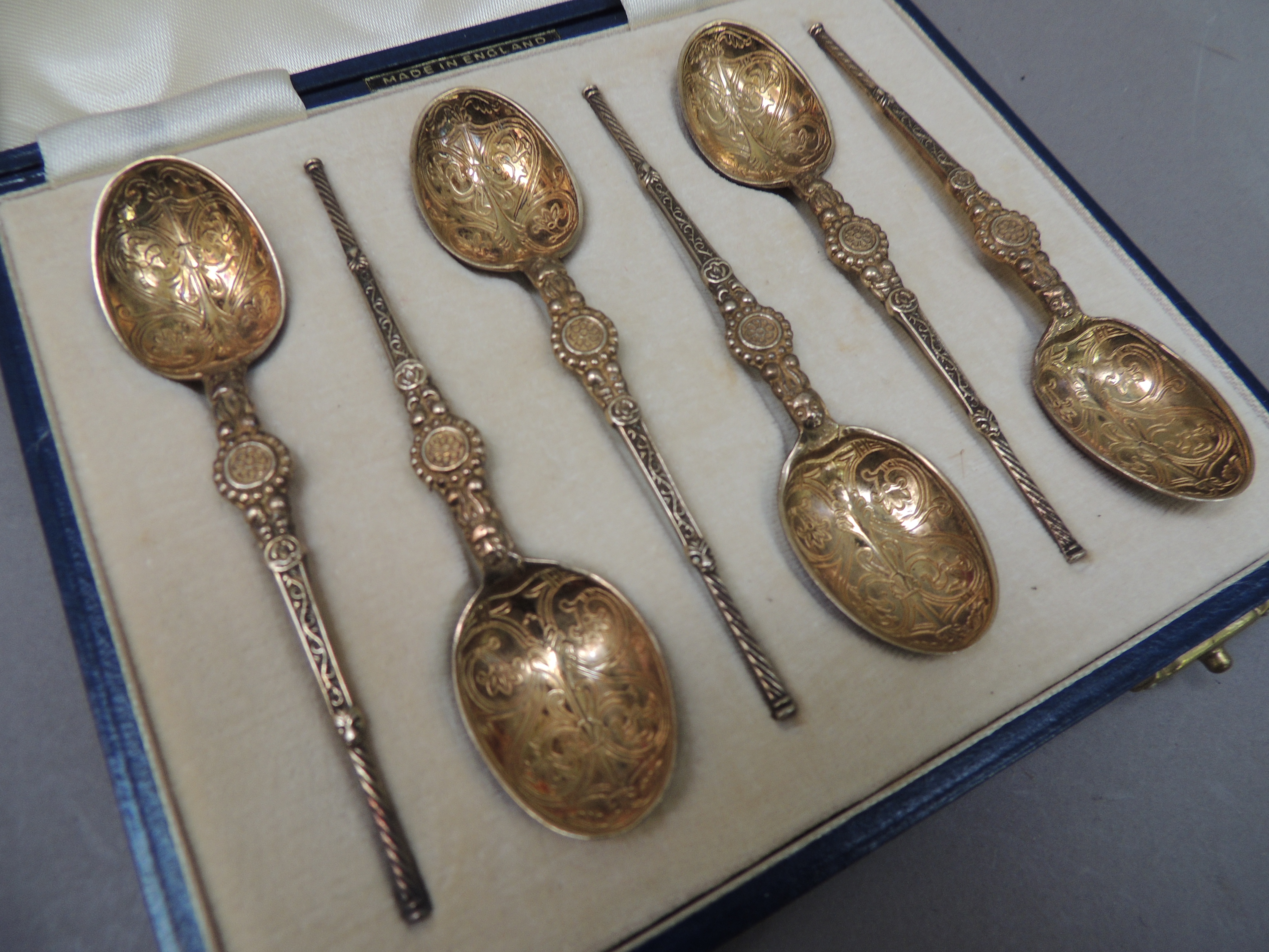 A cased set of silver gilt teaspoons in Elizabethan style with engraved bowls and cast tapered stems