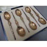 A cased set of silver gilt teaspoons in Elizabethan style with engraved bowls and cast tapered stems