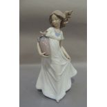 A Nao porcelain figure of a young girl carrying a two handled vase under her arm with a bird