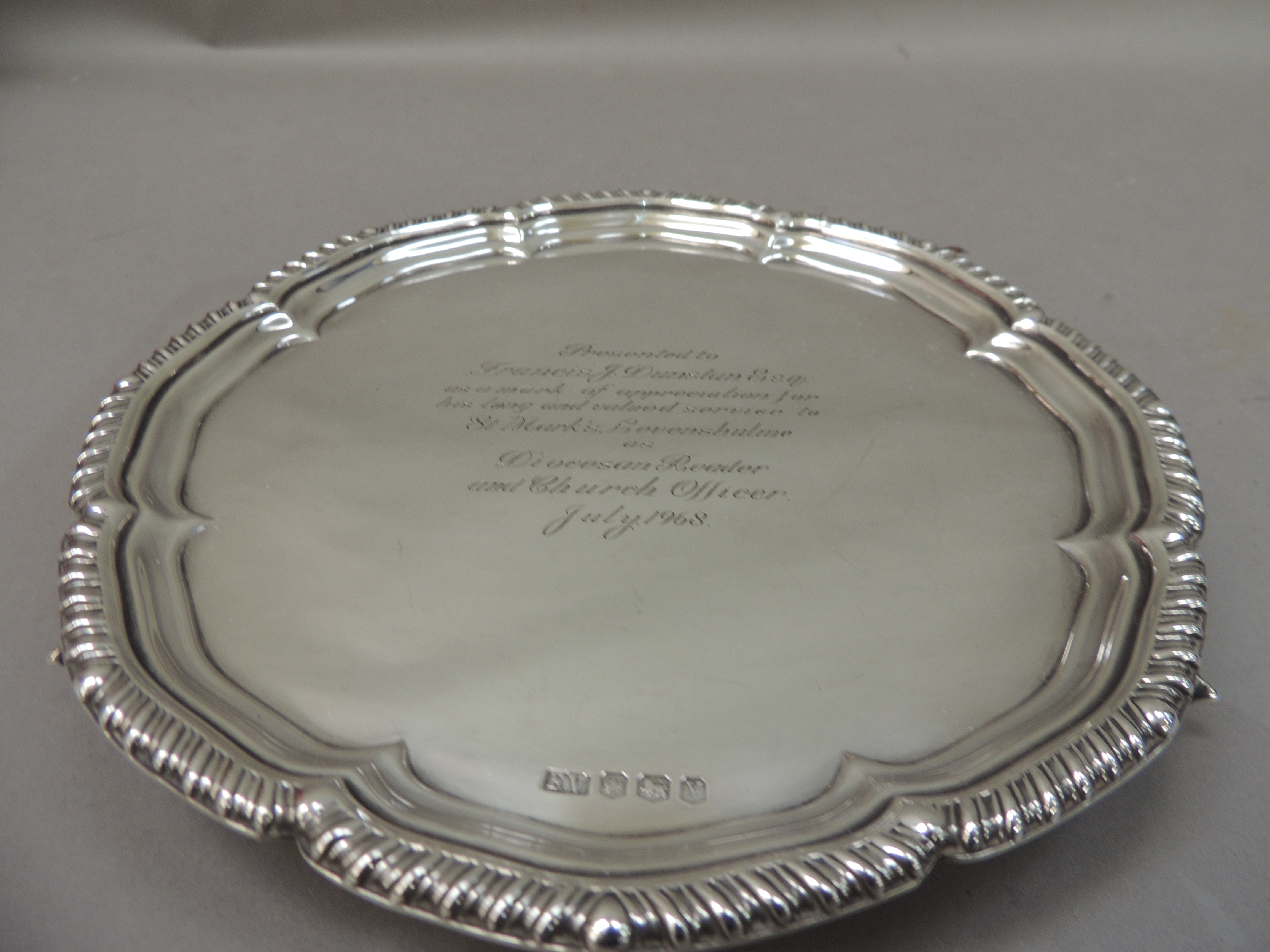 A George III style silver salver with gadrooned rim, the centre bearing presentation inscription,